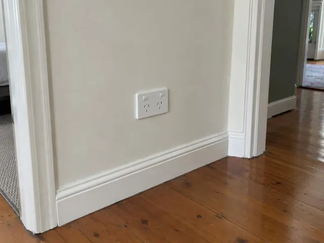 White double power point on a painted hallway wall above timber floorboards in Naremburn